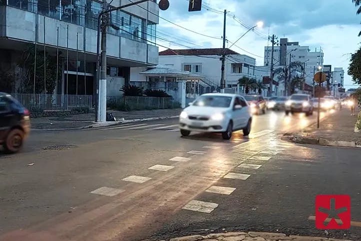 imagem colorida com veículos transitando em rua no centro de Patos de Minas