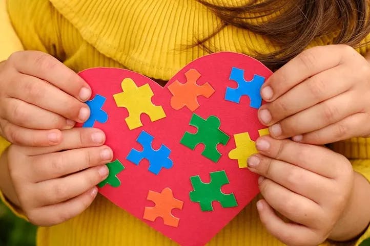 imagem colorida com criança segurando simbolo da conscientização do autismo