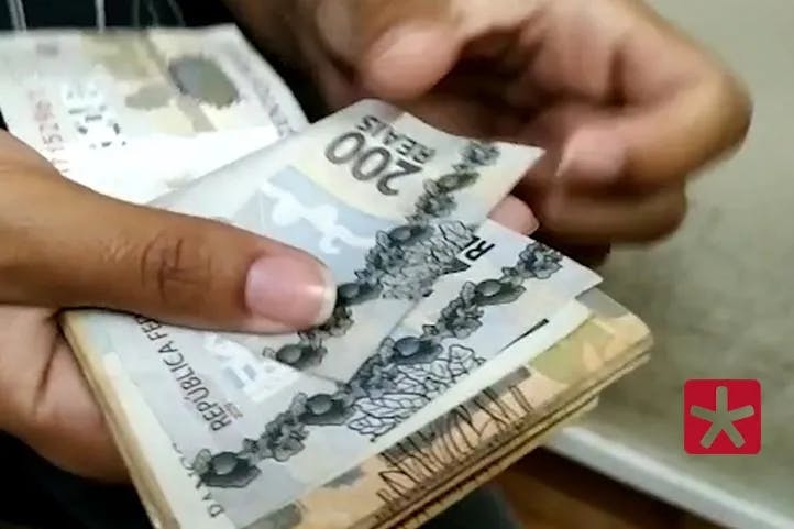 Imagem colorida mostrando dinheiro na mão, com as notas sendo contadas