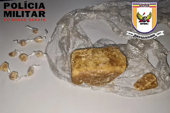  Fotografia contendo logomarcas da Polícia Militar e PMRV, mostrando nove pedras pequenas de crack e outras duas de tamanho grande e médio.
