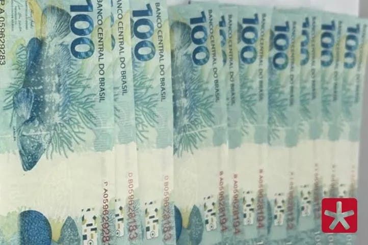 Fotografica colorida mostrando as 10 notas de 100 reais falsificadas, em cima de uma mesa
