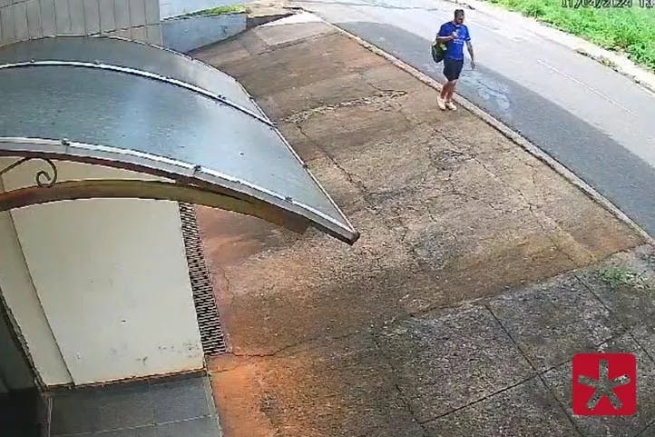 imagem de câmera de segurança mostrando homem de camiseta azul com uma mochila, caminhando pela calçada