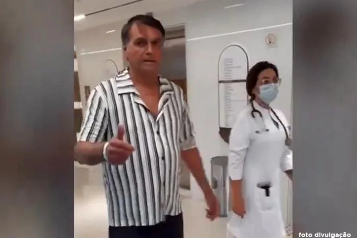 fotografia do ex-presidente Bolsonaro com roupa hospitalar fazendo joinha com a mão