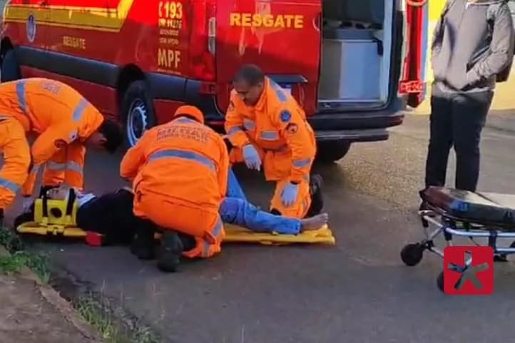 imagem colorida mostrando três socorristas do Corpo de Bombeiros, realizando atendimento a mulher vítima de acidente, deitada sobre a maca ao lado da viatura