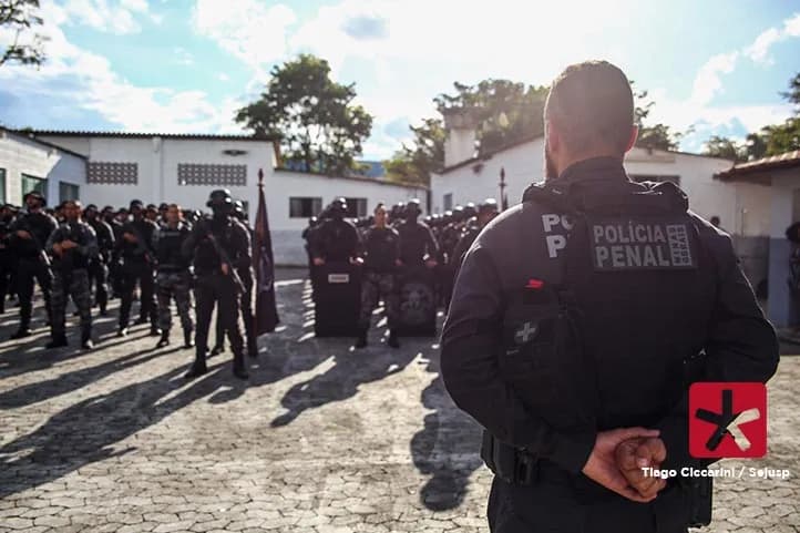 Imagem colorida mostrando tropa de policiais penais perfilados lado a lado e o comandante de costas