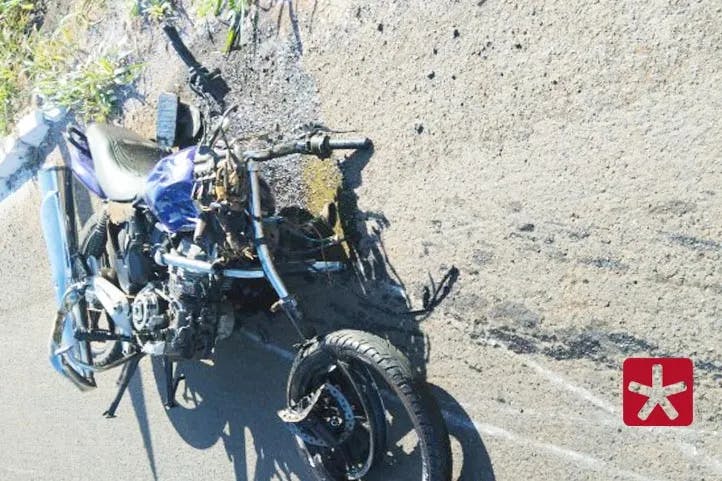 imagem colorida mostrando motocicleta de cor azul com toda a frente destruida, além da roda dianteira e outros danos