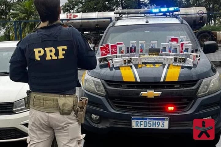 Imagem colorida, com policial da PRF de costas em frente a viatura com os materiais dispostos no capô